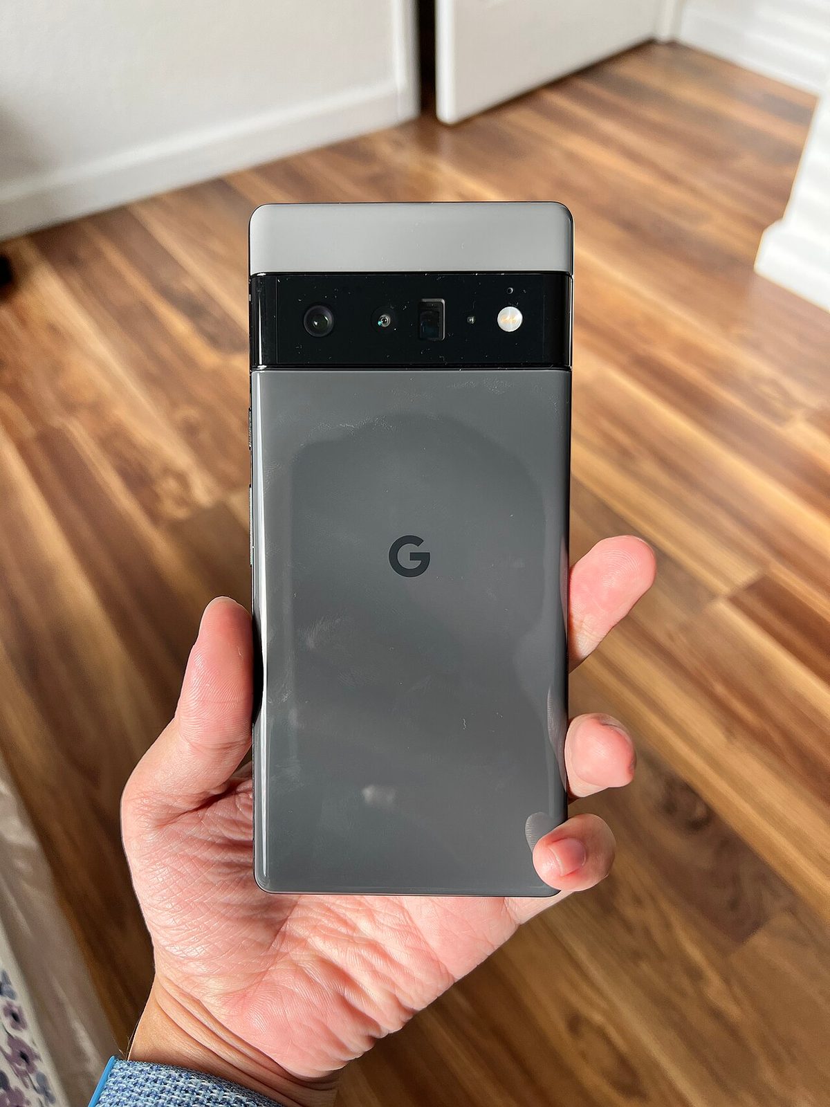 Google Pixel 6 Pro in Stormy Black held in a hand, rear view showing the three-camera bar