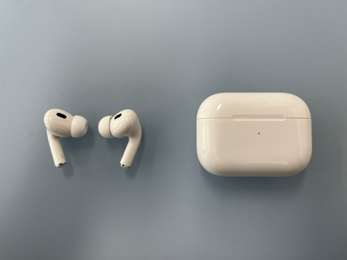 Apple AirPods Pro (2nd generation) earbuds and charging case laid flat on a grey surface